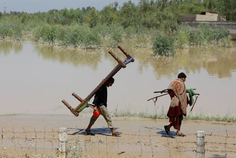 &copy; Reuters. باكستانيون يسيرون حاملين ممتلكات لهم بعد أمطار وفيضانات خلال موسم الرياح الموسمية في تشارسادا بباكستان يوم الأحد. تصوير: فياض عزيز - رويترز