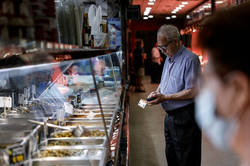 © Reuters. FILE PHOTO: A customer gets ready to pay at Hermanos Cadenas grocery store at a local market in Madrid, Spain, August 12, 2022. REUTERS/Susana Vera