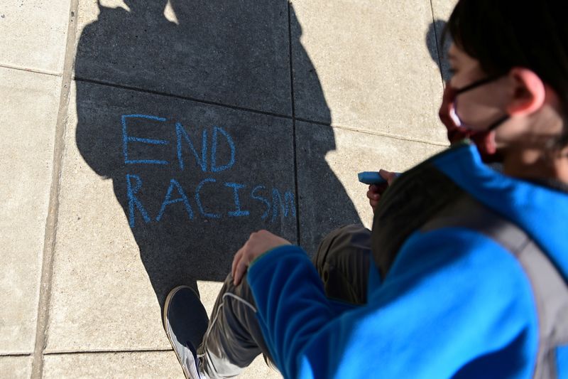 &copy; Reuters. FILE PHOTO: A child writes, "End racism" in chalk on a sidewalk as people rally to protest recent violence against people of Asian descent, in Washington, U.S. March 21, 2021. REUTERS/Erin Scott/File Photo