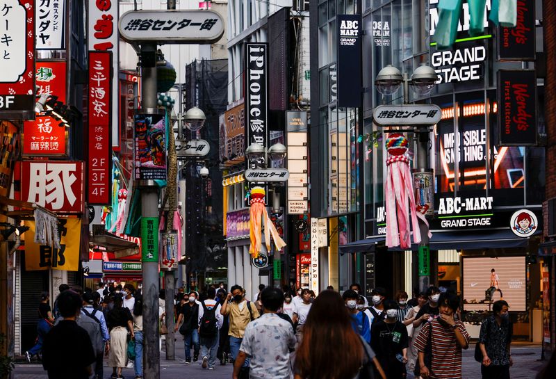 &copy; Reuters. FILE PHOTO: Passersby wearing protective face masks walk on the street at Shibuya shopping and amusement district, amid the coronavirus disease (COVID-19) pandemic, in Tokyo, Japan July 28, 2022.  REUTERS/Issei Kato