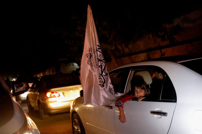 &copy; Reuters. طفلة أفغانية تطل من داخل سيارة تسير في شوارع كابول يوم 30 من أغسطس آب 2022 وترفع علما عليه شعار إمارة أفغانستان الإسلامية في الاحتفالات بالذكرى