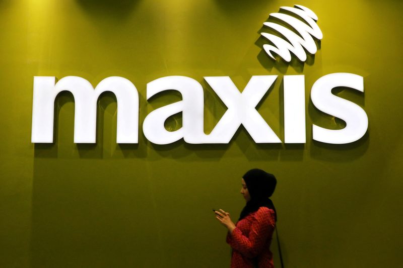 &copy; Reuters. FILE PHOTO: A woman walks past a logo of Maxis at its headquarters in Kuala Lumpur, Malaysia October 3, 2019. REUTERS/Lim Huey Teng