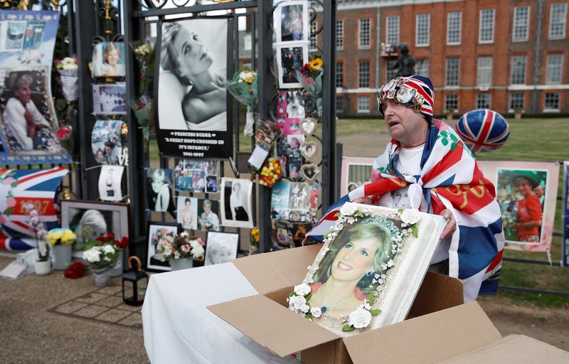© Reuters. أحد محبي الأميرة ديانا يعرض كعكة تحمل صورتها خارج قصر كينجستون بالعاصمة البريطانية لندن يوم الأربعاء تخليدا لذكرى مرور 25 عاما على وفاتها. تصوير : بيتر نيكولز- رويترز .   
