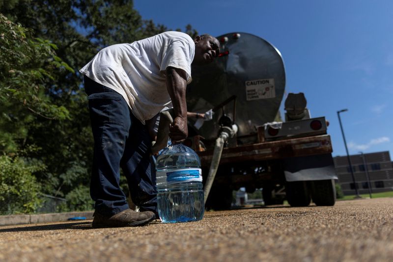 © Reuters. A local worker pours water into a bottle at a water distribution site at Forest Hill High School as the city of Jackson is to go without reliable drinking water indefinitely after pumps at the water treatment plant failed, leading to the emergency distribution of bottled water and tanker trucks for 180,000 people, in Jackson, Mississippi, U.S., August 31, 2022. REUTERS/Carlos Barria