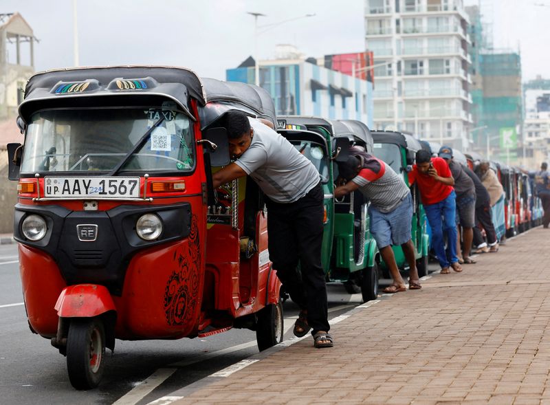 &copy; Reuters. 　９月１日、経済危機に陥っているスリランカは、国際通貨基金（ＩＭＦ）から約２９億ドルの金融支援を受けることで暫定合意した。写真はガソリンをいれるために車を押して行列に並べ