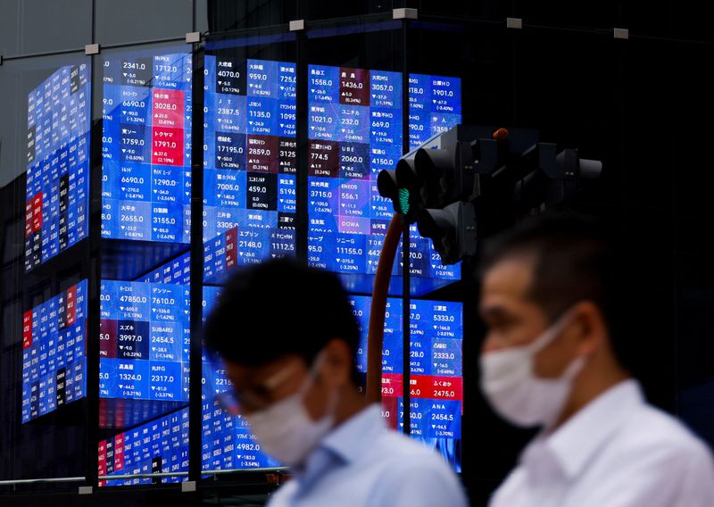 &copy; Reuters. FILE PHOTO: People pass by an electronic screen showing Japan's Nikkei share price index inside a conference hall  in Tokyo, Japan June 14, 2022. REUTERS/Issei Kato