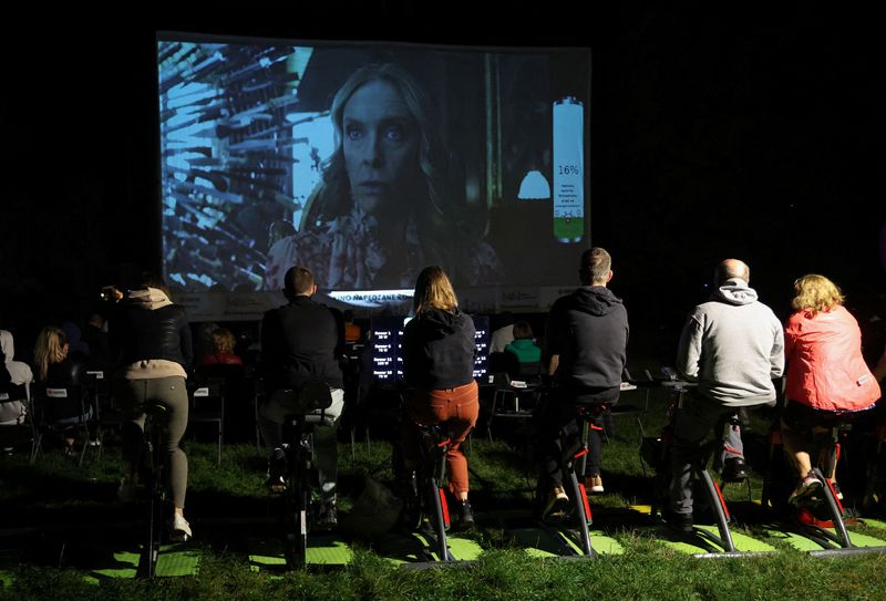 &copy; Reuters. People pedal stationary bikes and generate up to 50% of the energy at a pop-up outdoor cinema in a park in Warsaw, Poland September 2, 2022. REUTERS/Kacper Pempel