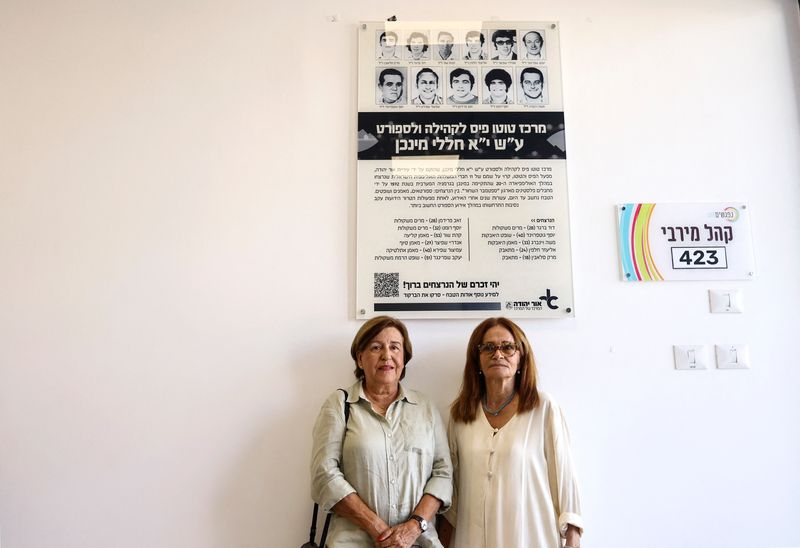 © Reuters. Ankie Spitzer and Ilana Romano, widows of Israeli athletes Andre Spitzer and Joseph Romano, stand by a placard during the inauguration ceremony of a sports centre dedicated to the memory of 11 Israeli athletes who were murdered in Munich 1972 olympic games Palestinian attack, ahead of the 50th anniversary commemoration of the massacre in Munich, Germany, at Or Yehuda, Israel August 28, 2022. REUTERS/Ronen Zvulun