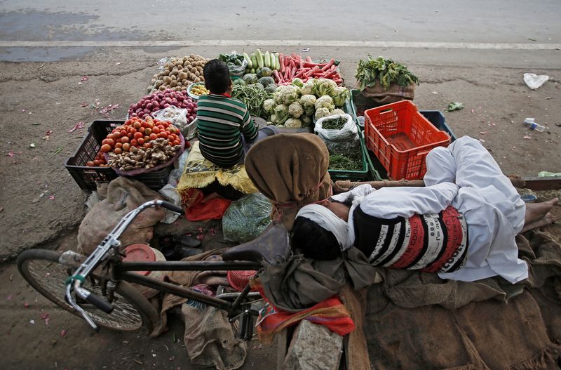 &copy; Reuters. A vendor sleeps as his son waits for customers at their roadside vegetable shop in New Delhi, India, February 12, 2019. REUTERS/Adnan Abidi