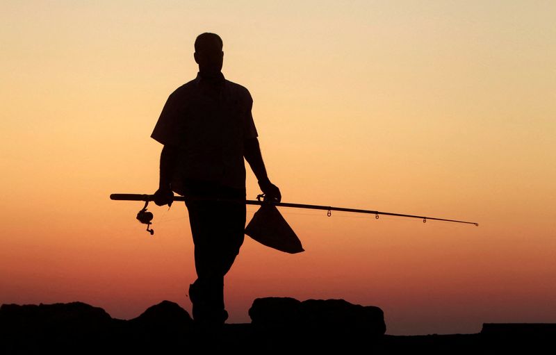 &copy; Reuters. Imagen de archivo de un hombre llevando una caña de pescar durante la puesta de sol a lo largo de la costa en la ciudad mediterránea de Alejandría, a 230 km al norte de El Cairo, Egipto. 12 de julio, 2011. Alejandría, con 4 millones de habitantes, es 