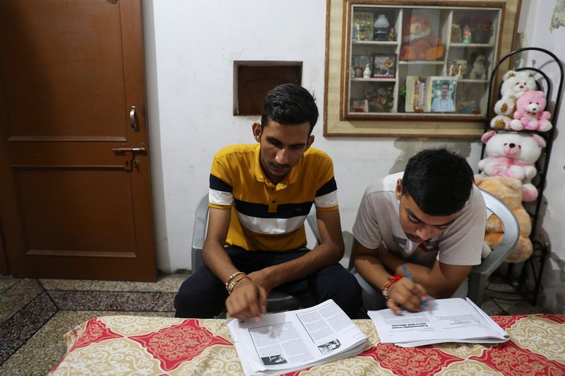 &copy; Reuters. Vijay Chauhan, 18, and Vishal, 18, who both take English language classes at Western Overseas institute, go through their notes at Vijay's house in the village of Adhoya in Ambala district, India, August 15, 2022. REUTERS/Anushree Fadnavis