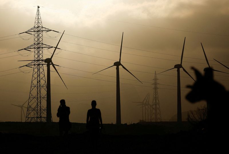 &copy; Reuters. FILE PHOTO: Two people walk near an electricity pylon and a group of wind turbines, in Barranco de Tirajana, in the island of Gran Canaria, Spain, May 11, 2022. REUTERS/Borja Suarez