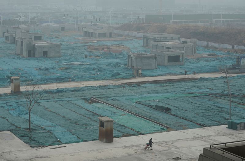 &copy; Reuters. FILE PHOTO: A man walks next to a construction site in Zhengzhou, Henan province, China January 13, 2020. REUTERS/Jason Lee