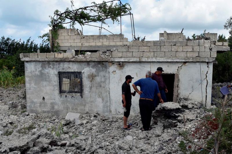 © Reuters. أفراد يتفحصون منطقة لحقت بها أضرار بعد ما قالت وزارة الدفاع السورية إنه 