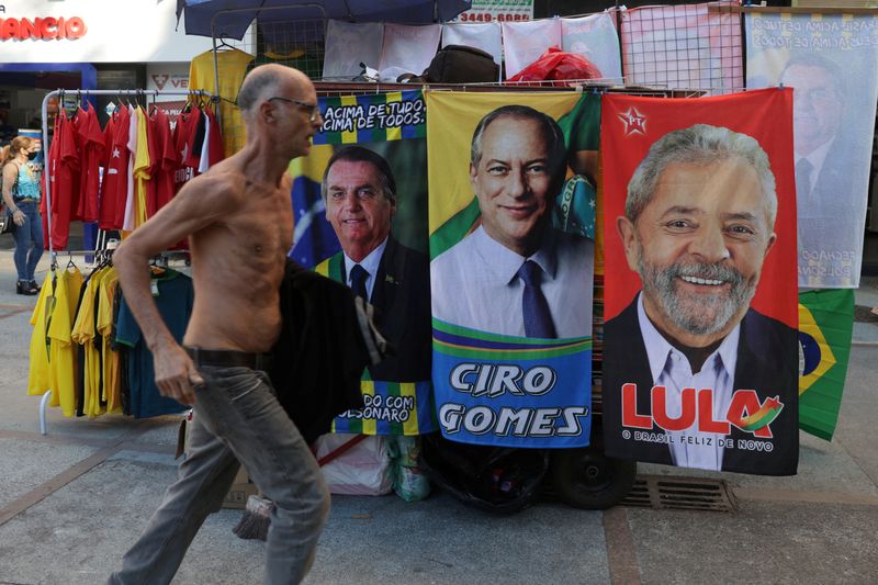 &copy; Reuters. No Rio de Janeiro, homem corre diante de barraca com banners alusivos aos candidatos à presidência
01/09/2022 
REUTERS/Pilar Olivares