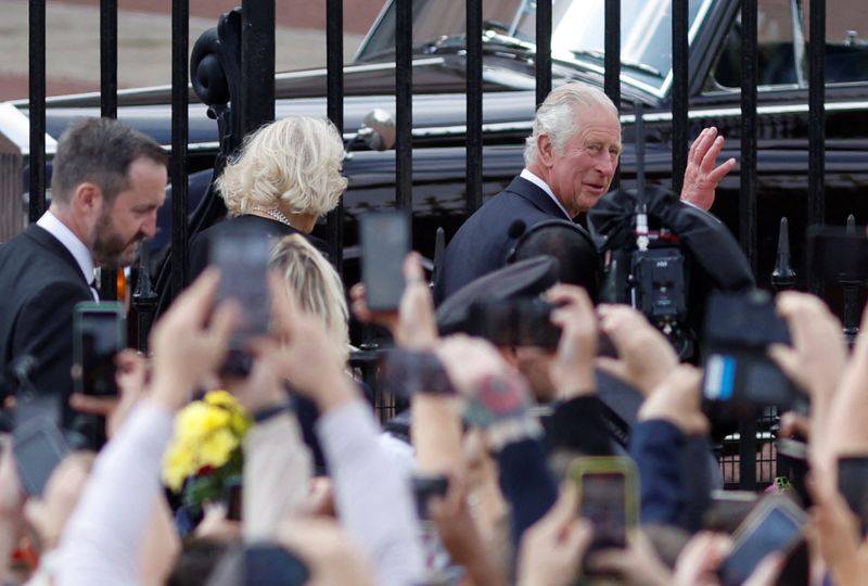 © Reuters. أفراد من العامة يحيون الملك تشارلز ملك بريطانيا وعقيلته كاميلا خارج قصر بكنجهام يوم الجمعة. تصوير : جون سيبلي- رويترز . 