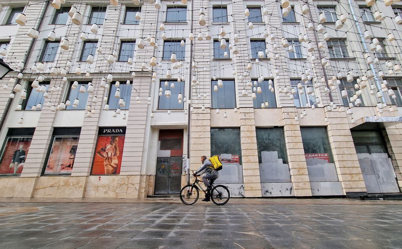 &copy; Reuters. FILE PHOTO: A Yandex Food courier rides a bicycle past the temporarily closed Prada shop and business property put out for rent, in Stoleshnikov Lane, which is one of the city's most expensive shopping areas accommodating numerous boutiques and luxury sho