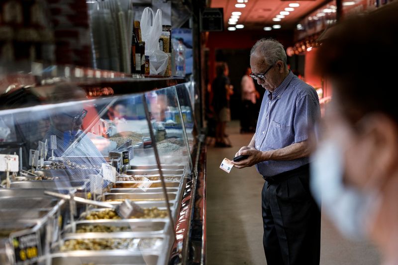 &copy; Reuters. A customer gets ready to pay at Hermanos Cadenas grocery store at a local market in Madrid, Spain, August 12, 2022. REUTERS/Susana Vera