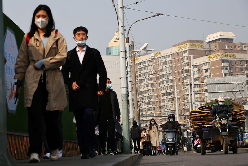 &copy; Reuters. Des personnes portent des masques de protection dans une rue de Pékin lors de la pandémie liée au coronavirus (COVID-19) en Chine. /Photo prise le 25 octobre 2021/REUTERS/Thomas Peter