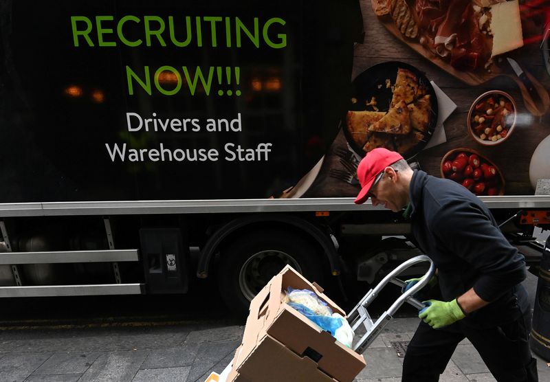 © Reuters. FILE PHOTO: A lorry driver passes a sign on the side of his vehicle advertising for jobs as he makes a delivery, in London, Britain, October 13, 2021. REUTERS/Toby Melville