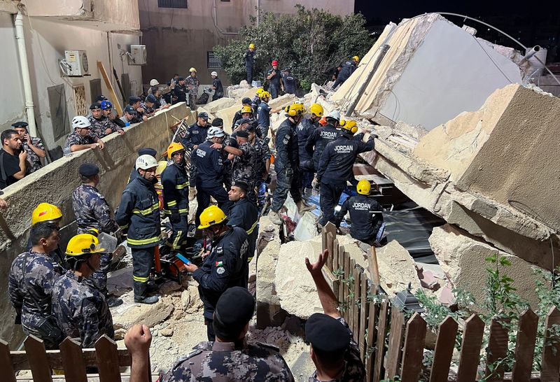 © Reuters. أفراد الحماية المدنية يعملون في موقع انهيار مبنى سكني مؤلف من أربعة طوابق في عمان يوم الثلاثاء. تصوير: جهاد شلباق - رويترز