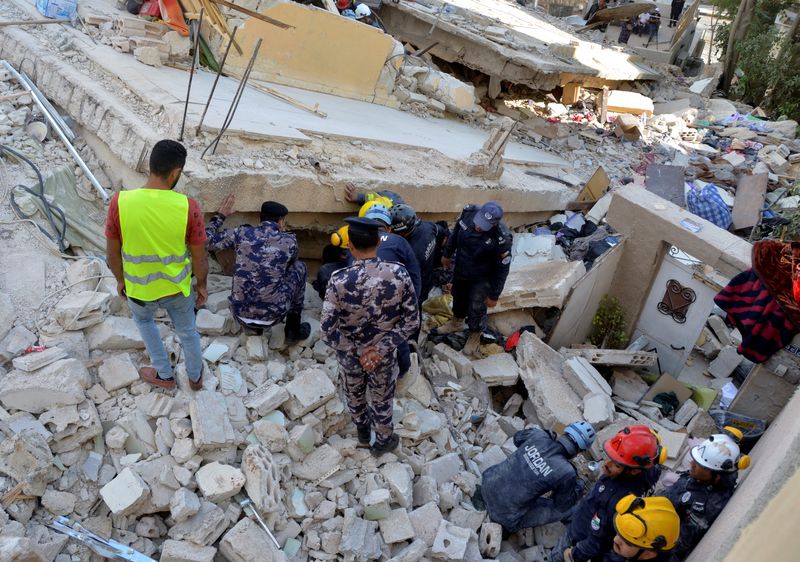 &copy; Reuters. عمال الإنقاذ يبحثون عن ناجين وسط حطام مبنى منهار في عمان يوم الأربعاء. تصوير: معاذ فريج - رويترز