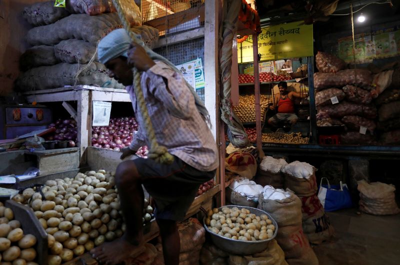 © Reuters. FILE PHOTO: A vendor climbs to his stall as another waits for customers at a wholesale vegetable market in Mumbai, India, March 14, 2018. REUTERS/Danish Siddiqui