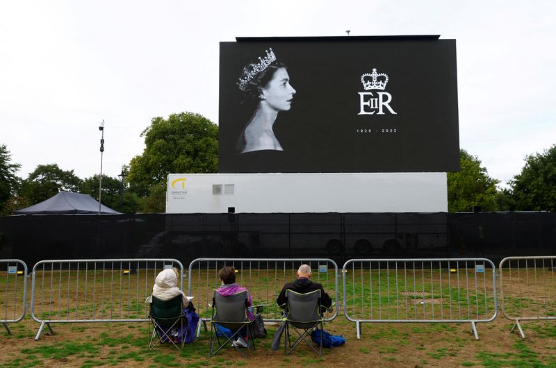 &copy; Reuters. Royal fans Isabel Litherland, Martine Knight and Chris Knight sit in Hyde Park where the screening of the procession of the coffin of Britain's Queen Elizabeth will take place, in London, Britain, September 14, 2022.  REUTERS/Andrew Boyers    
