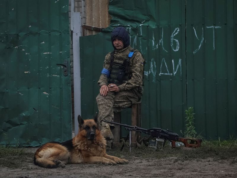&copy; Reuters. Ukrainian serviceman patrols an area as a dog sits near by, as Russia's attack on Ukraine continues, in the town of Izium, recently liberated by Ukrainian Armed Forces, in Kharkiv region, Ukraine September 14, 2022. REUTERS/Gleb Garanich    