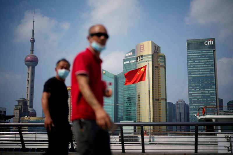 &copy; Reuters. FILE PHOTO: People wearing face masks following the coronavirus disease (COVID-19) outbreak walk past a Chinese flag in Shanghai, China August 2, 2022. REUTERS/Aly Song/File Photo