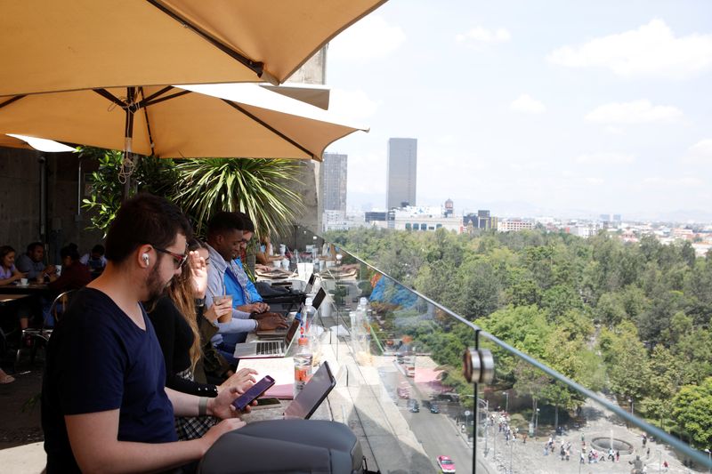 &copy; Reuters. 　９月１３日、市内のカフェや公園、民泊施設には、世界各地から多数の訪問者が流れ込んでいる。写真はメキシコ市のコーヒーショップでノートパソコンを開き働く人々。９日撮影（２０