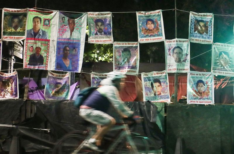 © Reuters. Grade com fotos de alguns dos 43 alunos que desapareceram da Escola de Professores Rurais de Ayotzinapa depois que o ex-procurador-geral Jesus Murillo foi preso sob a acusação de desaparecimento forçado, tortura e obstrução da justiça no desaparecimento de 43 alunos em 2014, na Avenida Reforma, em Cidade do México, México 
19/08/2022
REUTERS/Henry Romero