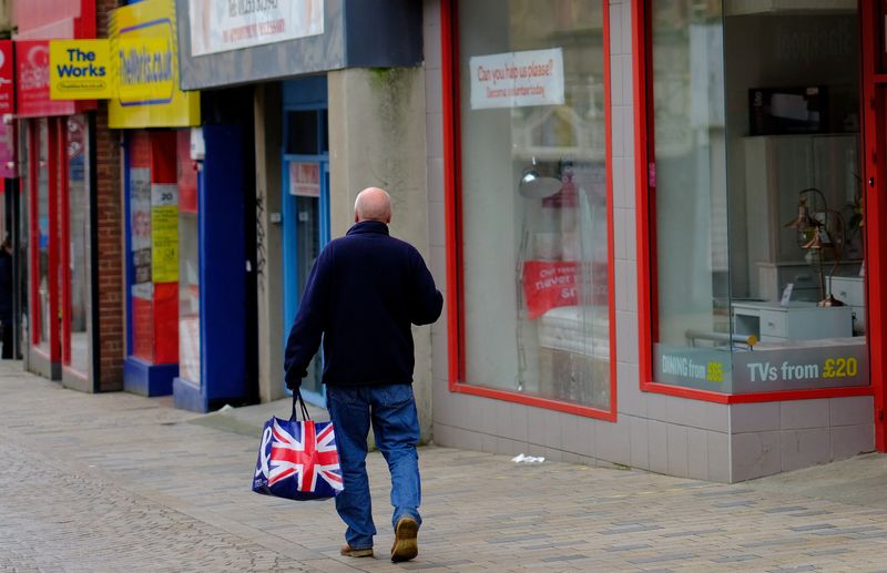 &copy; Reuters. FILE PHOTO: A man carries a Union Jack themed shopping bag as he walks along an empty shopping street in Blackpool, Britain, March 9, 2021. REUTERS/Phil Noble/File Photo