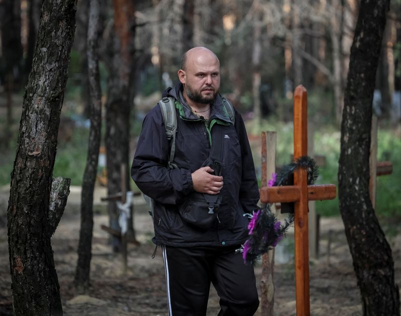 &copy; Reuters. شخص يبحث بين القبور عن أقارب له في مقبرة جماعية ببلدة إيزيوم في منطقة خاركيف التي حررتها القوات الأوكرانية من الروس في صورة التقطت يوم السبت