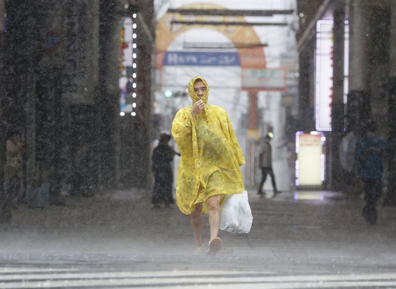 &copy; Reuters. Un homme marche dans la rue sous les fortes pluies et le vent provoqués par le typhon Nanmadol à Kagoshima, sur l'île principale de Kyushu, la plus au sud du Japon. /Photo prise  le 18 septembre 2022/REUTERS/Kyodo 