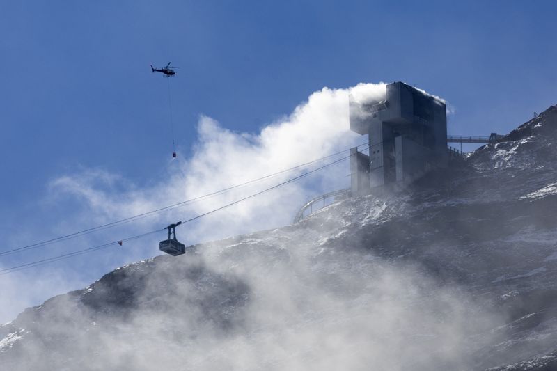 &copy; Reuters. An helicopter carries water to stop an ongoing fire at the restaurant Botta at the Glacier 3000 resort in Les Diablerets, Switzerland, September 19, 2022.  REUTERS/Denis Balibouse
