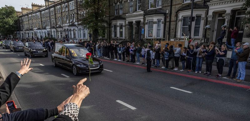 © Reuters. شخص يلقي وردة تجاه نعش الملكة إليزابيث في لندن يوم الاثنين. تصوير: كارلوس باريا - رويترز