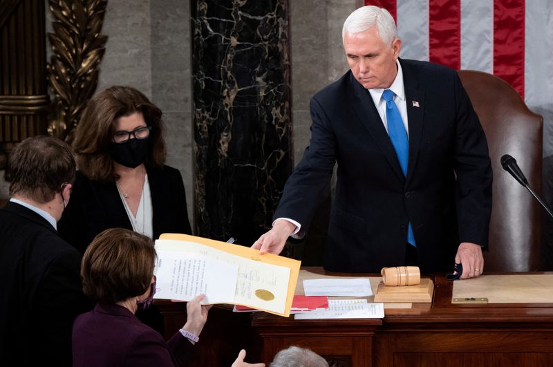 © Reuters. FILE PHOTO: US Vice President Mike Pence hands the electoral certificate from the state of Arizona to US Senator Amy Klobuchar, Democrat of Minnesota, as he presides over a joint session of Congress to certify the 2020 election results on Capitol Hill in Washington, U.S., January 6, 2021. Saul Loeb/Pool via REUTERS/File Photo