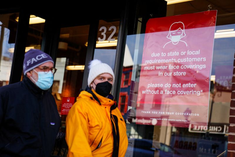 &copy; Reuters. FILE PHOTO: People wearing protective face masks walk past a business displaying a sign requiring face coverings during the coronavirus disease (COVID-19) pandemic in Washington, U.S. January 31, 2022.    REUTERS/Sarah Silbiger