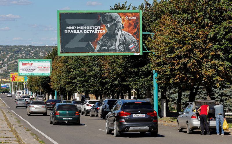 &copy; Reuters. Vehicles drive past advertising boards, including panels displaying pro-Russian slogans, in a street in the course of Russia-Ukraine conflict in Luhansk, Ukraine September 20, 2022. One of the boards reads: "World changes - truth stays. Army of Russia". R