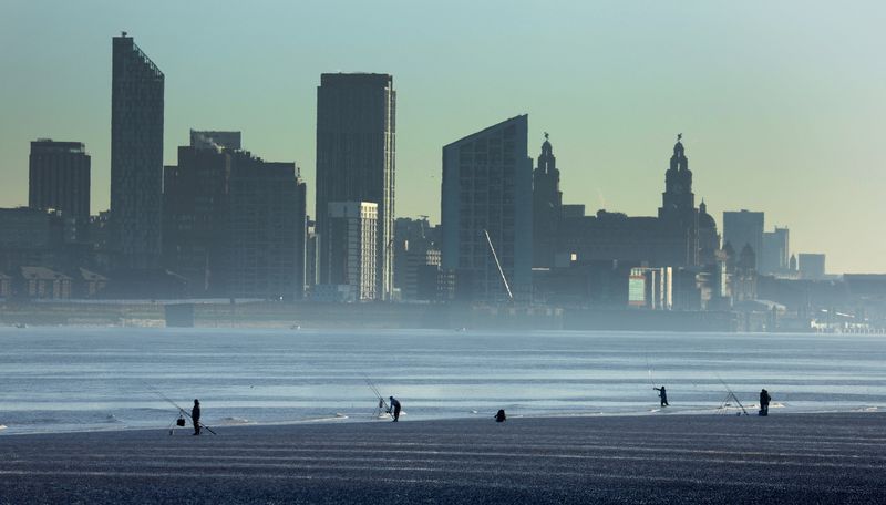 &copy; Reuters. FILE PHOTO: People fish in front of the skyline of Liverpool on the banks of the River Mersey in Wallasey, Britain, January 13, 2022. REUTERS/Phil Noble