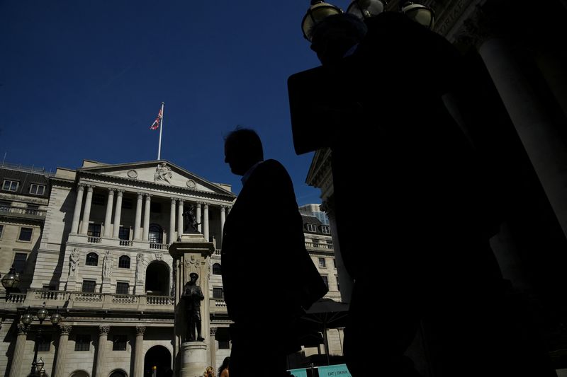 © Reuters. FILE PHOTO: Workers are silhouetted as they walk past the Bank of England, in London, Britain, August 8, 2022.  REUTERS/Toby Melville