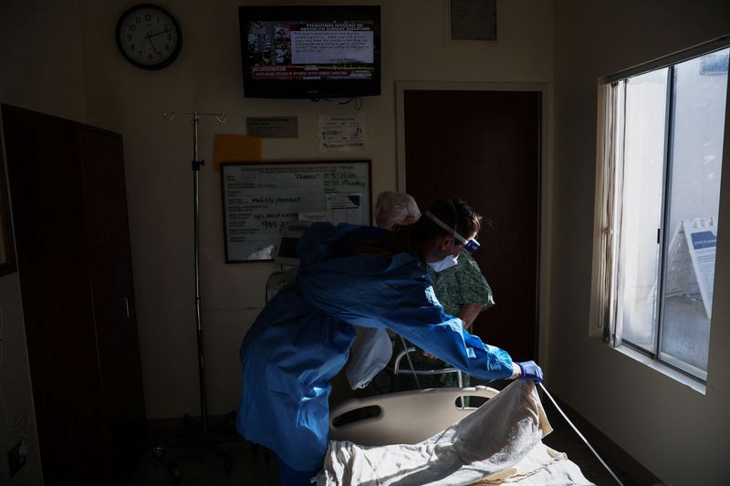 &copy; Reuters. Charles Brubaker, 99 ans, un patient du COVID-19 qui a été admis après s'être blessé à la hanche en s'isolant chez lui, est aidé par une infirmière pour se tenir debout pour une photo à l'intérieur de sa chambre d'isolement à l'hôpital Provide