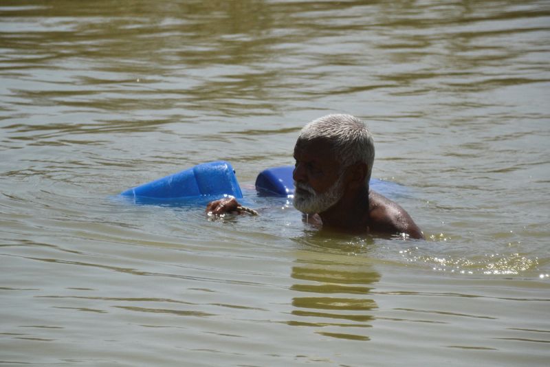 &copy; Reuters. FILE PHOTO: A man, displaced because of the floods, wades through flood water to fill the canisters, following rains and floods during the monsoon season in Sehwan, Pakistan September 20, 2022. REUTERS/Stringer/File Photo