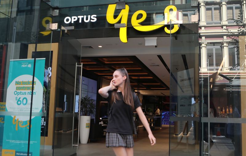 &copy; Reuters. A woman uses her mobile phone as she walks past in front of an Optus shop in Sydney, Australia, February 8, 2018. REUTERS/Daniel Munoz/File Photo