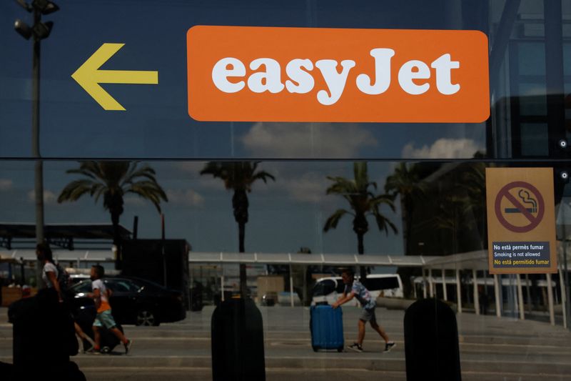 &copy; Reuters. Passengers reflected on a glass with an Easyjet logo on it walk at Josep Tarradellas Barcelona-El Prat Airport during an Easyjet's cabin crew strike, in Barcelona, Spain, July 1, 2022. REUTERS/Albert Gea