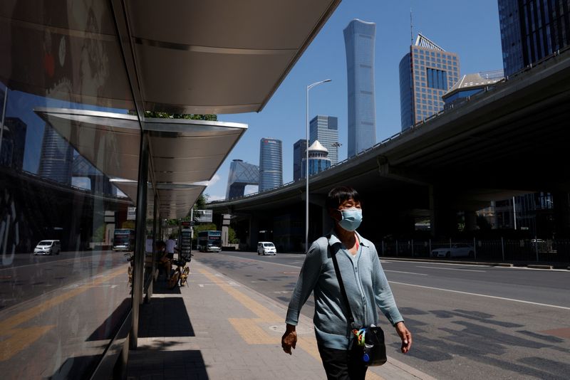 &copy; Reuters. امرأة تضع كمامة تسير بجوار محطة حافلات في بكين يوم 30 مايو أيار 2022. تصوير: كارلوس جارسيا راولينز - رويترز