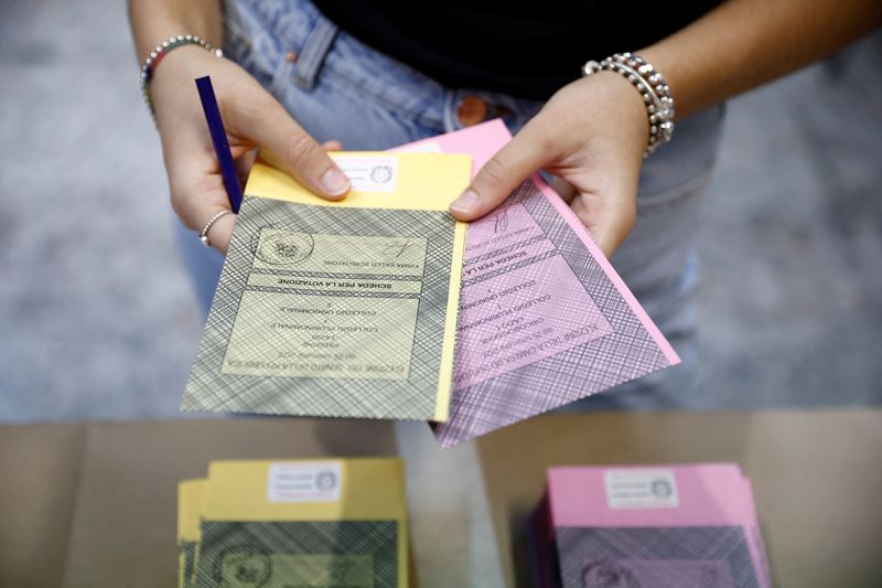 &copy; Reuters. امرأة تحمل أبطاقات اقتراع في مركز اقتراع خلال الانتخابات المبكرة في روما يوم الأحد. تصوير: جولييلمو مانجيابان - رويترز.