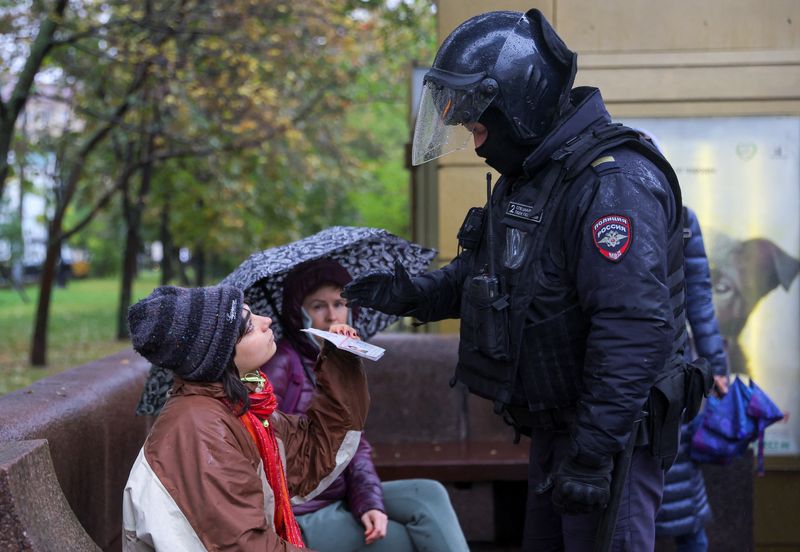 &copy; Reuters. شخص يعرض جواز سفر لضابط روسي خلال تجمع حاشد في موسكو يوم السبت. تصوير: رويترز.