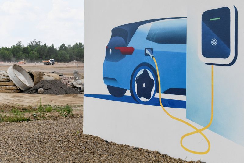 © Reuters. FILE PHOTO: A board showing an electric Volkswagen car at a charging station is pictured in front of the construction site of German carmaker Volkswagen's so called 